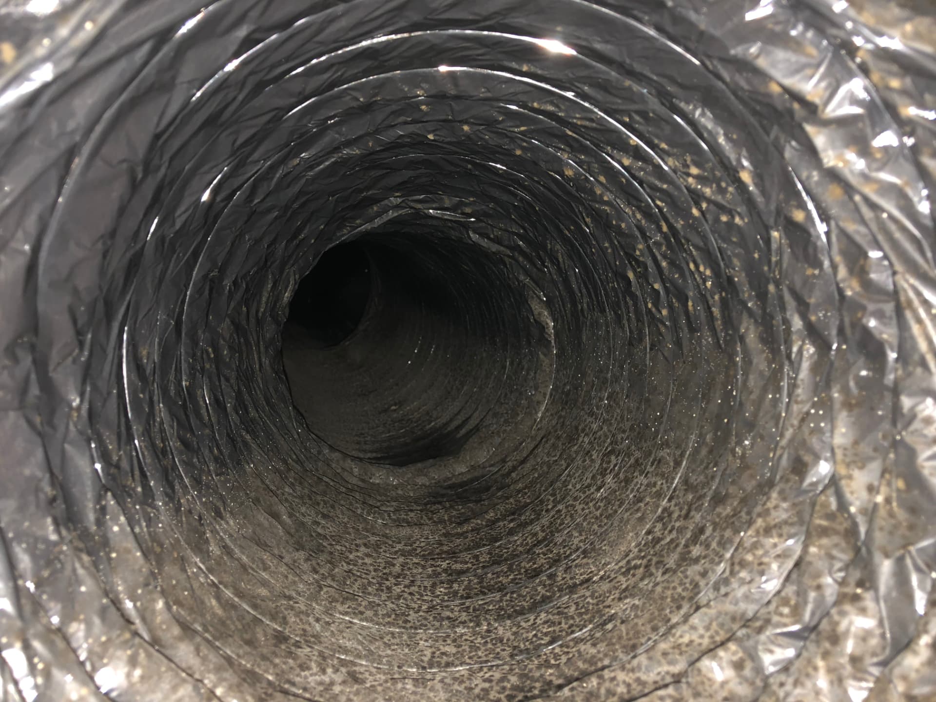 Interior de ducto de aire acondicionado con polvo y suciedad acumulada antes de la limpieza